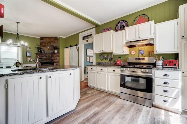 kitchen with white cabinets, a sink, stainless steel range with gas cooktop, under cabinet range hood, and ornamental molding