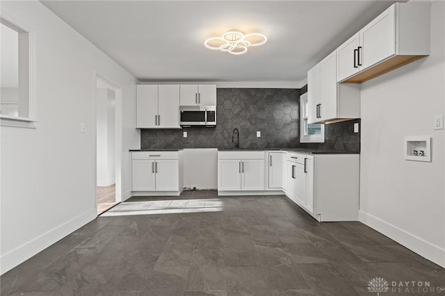 149 Poe Ln, Xenia, OH 45385 - kitchen featuring tasteful backsplash, a sink, baseboards, stainless steel microwave, and white cabinetry