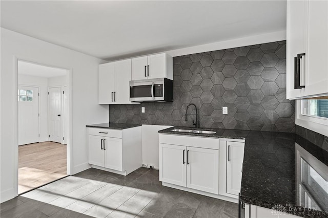 149 Poe Ln, Xenia, OH 45385 - kitchen featuring stainless steel microwave, white cabinets, tasteful backsplash, a sink, and dark stone countertops