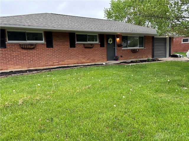 ranch-style house featuring a garage, a shingled roof, a front yard, and brick siding