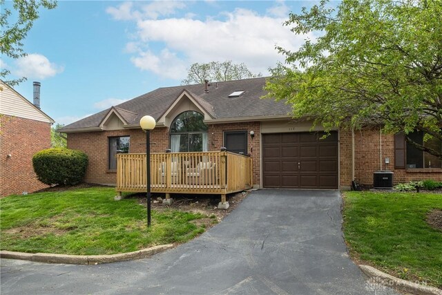 ranch-style house featuring a garage, a front lawn, brick siding, and aphalt driveway