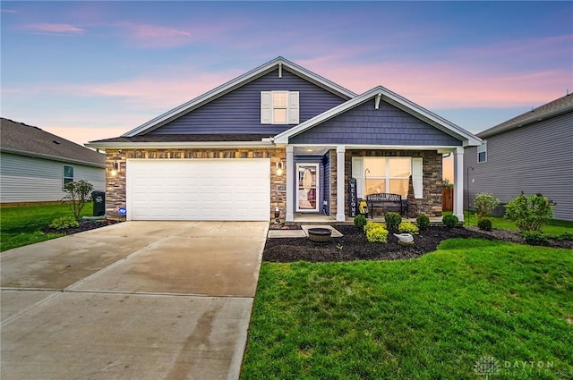 view of front of property featuring a yard, concrete driveway, and stone siding
