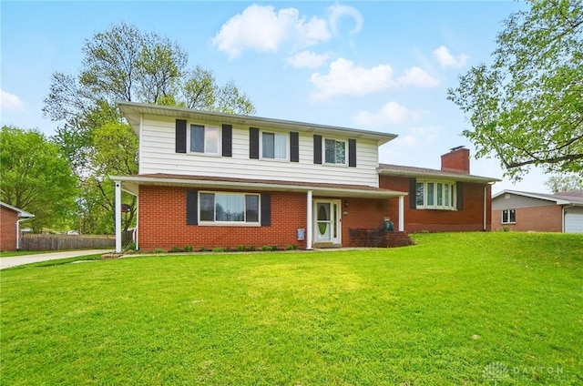 tri-level home featuring brick siding, a front lawn, fence, and a chimney