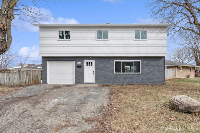view of front of home with brick siding, fence, driveway, and a garage