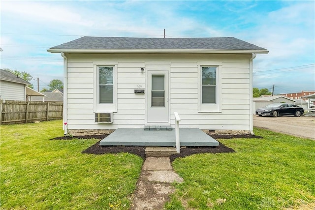 back of house with a lawn, a shingled roof, and fence