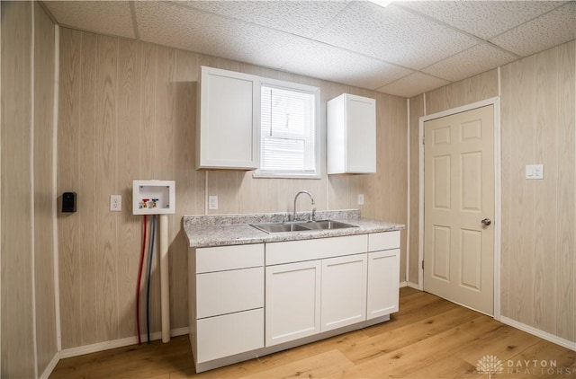 clothes washing area featuring a sink, wood walls, light wood-type flooring, and hookup for a washing machine