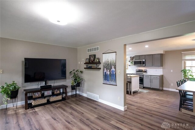 living room featuring baseboards, visible vents, and wood finished floors