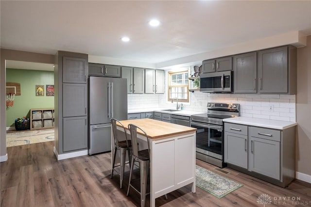 kitchen featuring butcher block countertops, decorative backsplash, appliances with stainless steel finishes, and gray cabinetry