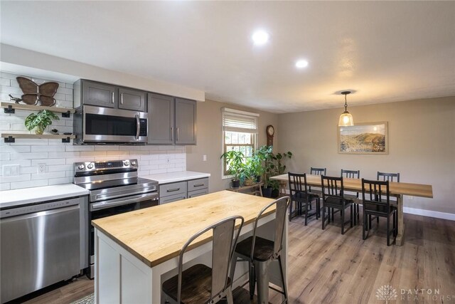 kitchen with open shelves, appliances with stainless steel finishes, light wood finished floors, wooden counters, and decorative backsplash