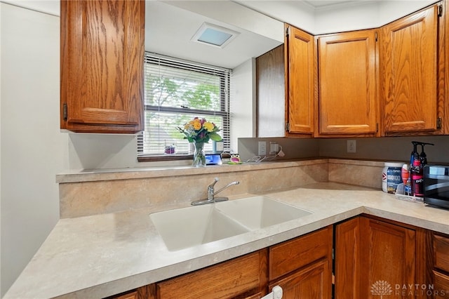 813 Kenosha Rd, Kettering, OH 45429 - kitchen with light countertops, black microwave, brown cabinetry, and a sink
