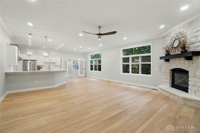 unfurnished living room featuring ornamental molding, a fireplace, baseboards, ceiling fan, and light wood finished floors