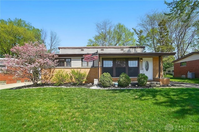 view of front facade featuring brick siding, central AC unit, and a front lawn