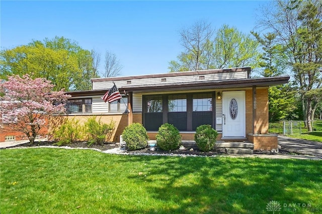 view of front facade featuring fence, a front lawn, and brick siding