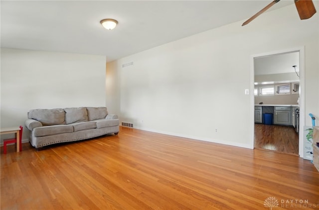 living room featuring visible vents, a ceiling fan, and light wood finished floors