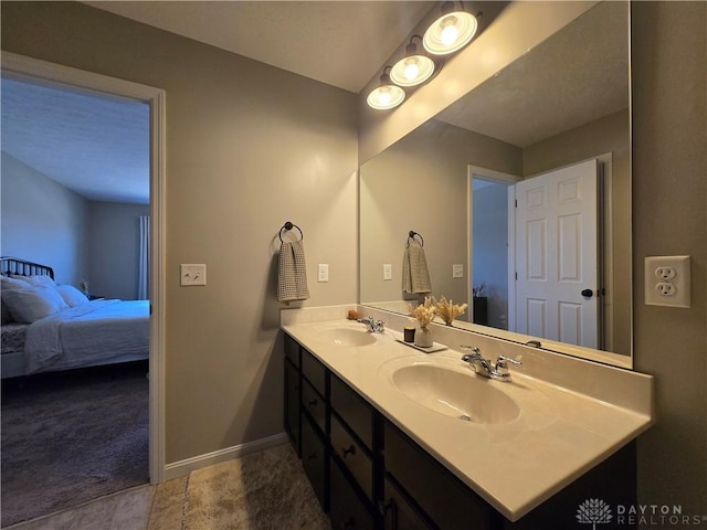 bathroom with double vanity, a sink, connected bathroom, and baseboards