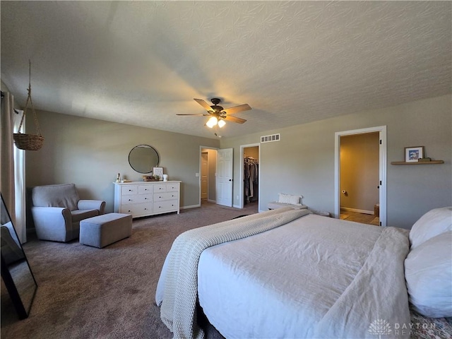 bedroom featuring visible vents, a closet, a walk in closet, a ceiling fan, and carpet