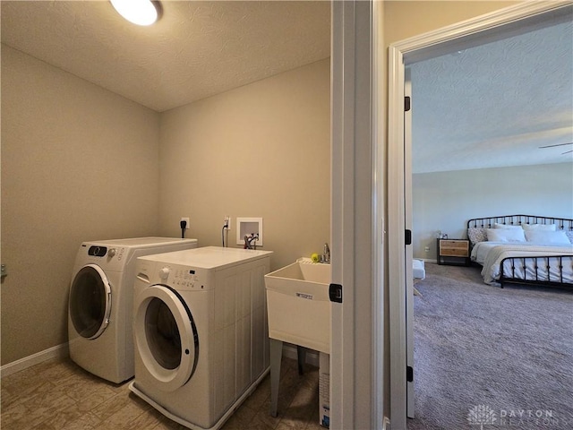 laundry room with carpet flooring, laundry area, a textured ceiling, baseboards, and washing machine and dryer