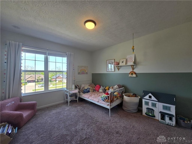 carpeted bedroom featuring a textured ceiling and baseboards