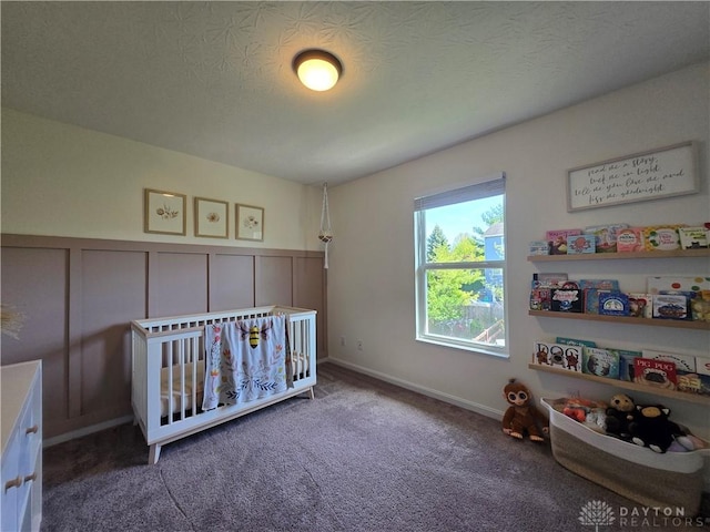 carpeted bedroom with wainscoting and a decorative wall