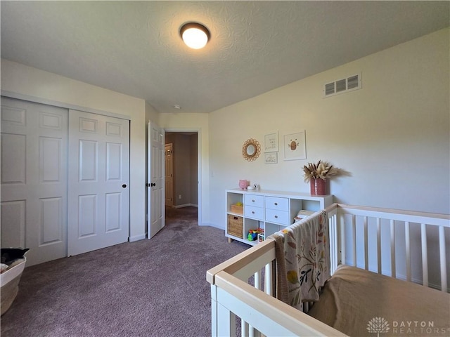 bedroom with visible vents, a closet, dark carpet, baseboards, and a textured ceiling