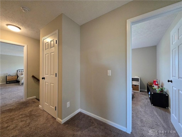 hallway with carpet and a textured ceiling