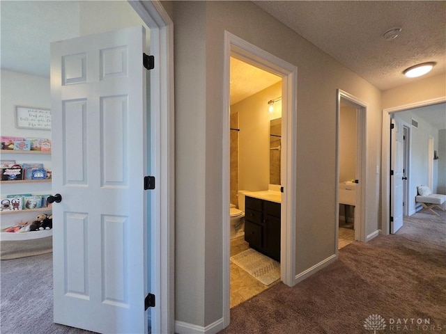 corridor featuring baseboards, dark carpet, and a textured ceiling
