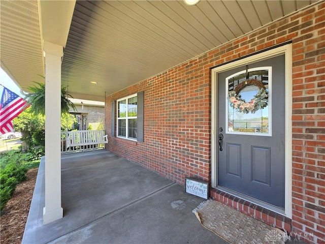 property entrance featuring a porch and brick siding