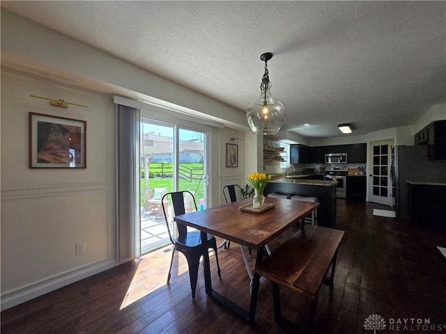 dining room featuring a textured ceiling, baseboards, and dark wood-type flooring