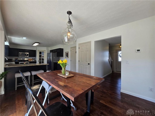 dining room with a textured ceiling, baseboards, and dark wood-type flooring