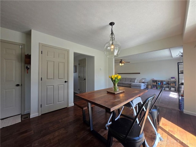 dining area featuring a textured ceiling, ceiling fan, dark wood finished floors, and baseboards
