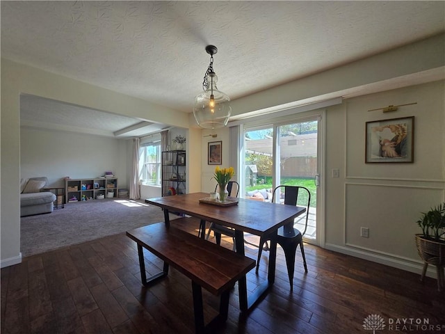 dining space featuring baseboards, dark wood-style floors, and a textured ceiling