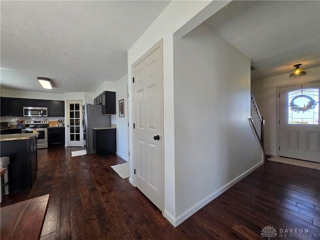 entryway featuring stairs, a textured ceiling, dark wood-style floors, and baseboards