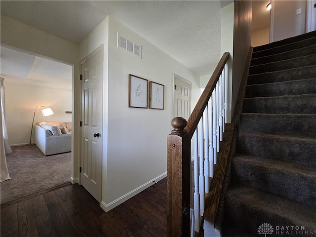 staircase featuring baseboards, hardwood / wood-style floors, and visible vents
