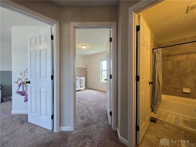 corridor featuring visible vents, carpet, and baseboards