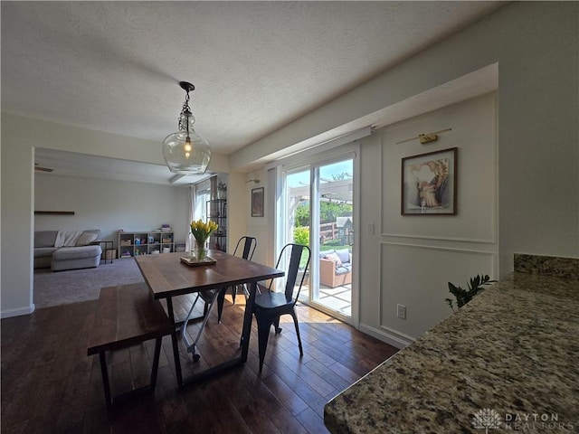 dining area with dark wood-type flooring, a textured ceiling, and baseboards