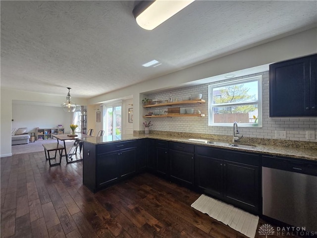 kitchen with light stone countertops, a sink, dishwasher, a textured ceiling, and dark wood finished floors