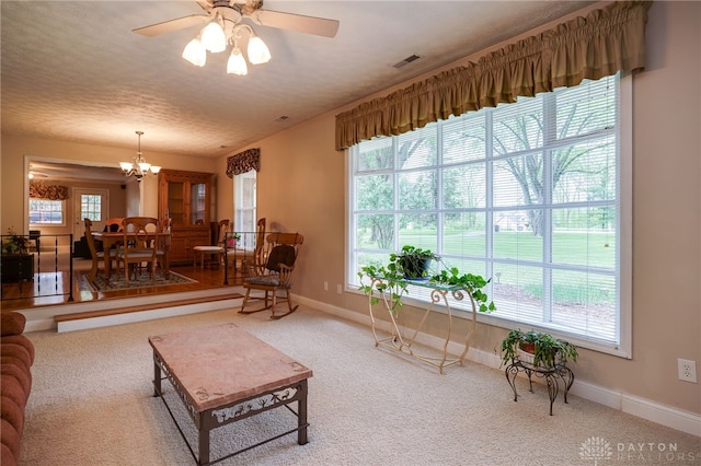 9550 Paragon Rd, Dayton, OH 45458 - carpeted living room featuring a textured ceiling, baseboards, visible vents, and ceiling fan with notable chandelier