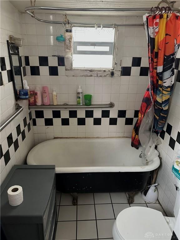 full bath featuring a bath, tile walls, tile patterned flooring, toilet, and a shower with shower curtain