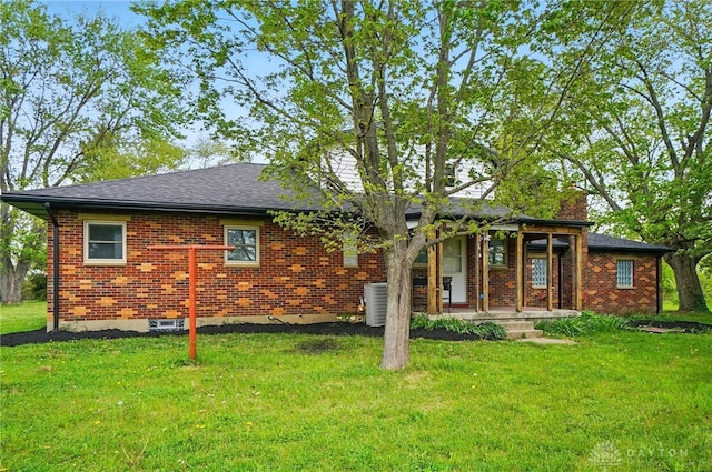 back of house featuring covered porch, brick siding, and a lawn