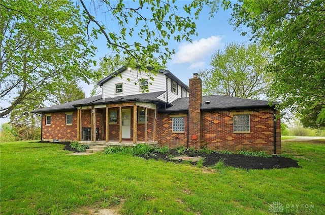rear view of house with roof with shingles, a chimney, a yard, and brick siding
