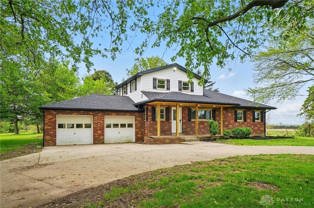 traditional-style house with covered porch, driveway, a front yard, a garage, and brick siding