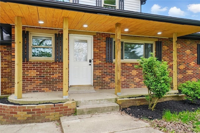 entrance to property with brick siding and a porch