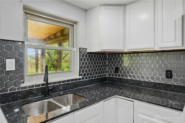 kitchen featuring a sink, white cabinetry, dark stone countertops, and decorative backsplash