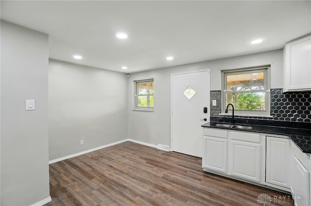 kitchen with dark wood-type flooring, recessed lighting, white cabinets, a sink, and backsplash