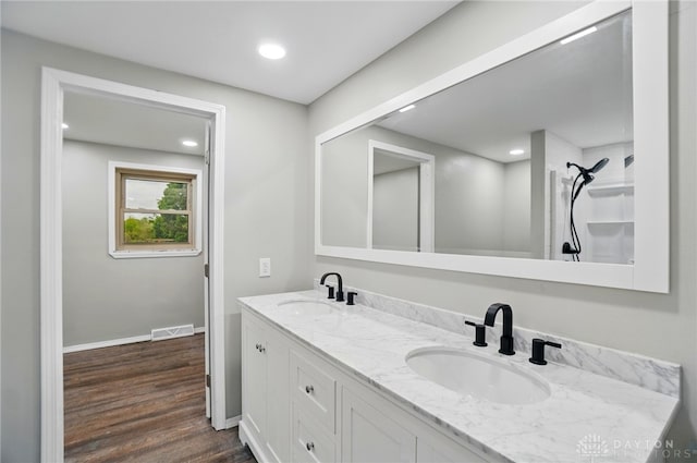 full bath with a sink, a shower, wood finished floors, and visible vents