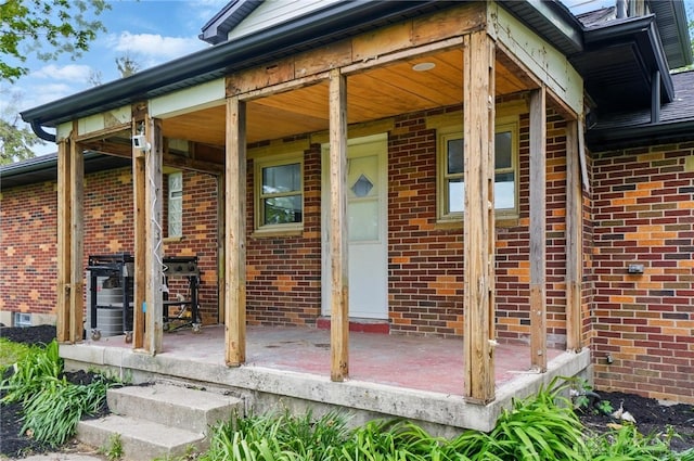 property entrance featuring a porch and brick siding