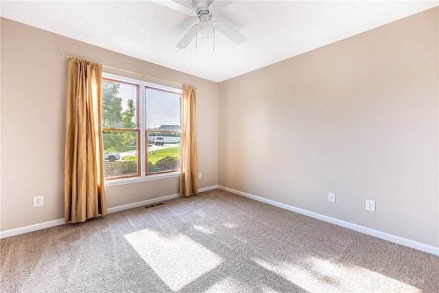 empty room with baseboards, a ceiling fan, carpet flooring, and visible vents