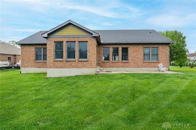 rear view of property with a lawn, a shingled roof, and brick siding