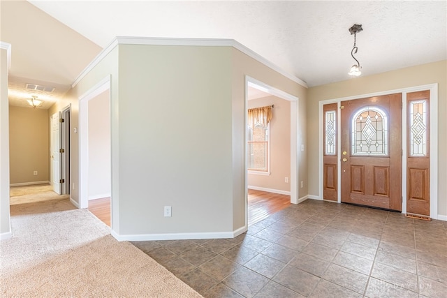 entrance foyer with crown molding, baseboards, and visible vents