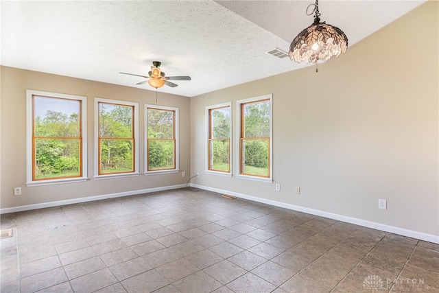 spare room featuring baseboards, ceiling fan, a textured ceiling, and visible vents
